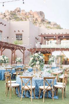 an outdoor reception setup with blue linens and wooden chairs