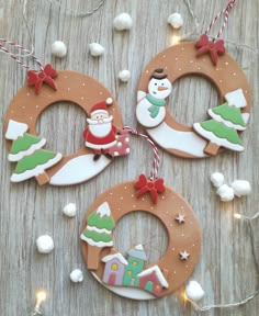 three christmas ornaments are hanging on a wooden table with snowman, santa clause and other decorations