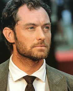 a close up of a person wearing a suit and tie