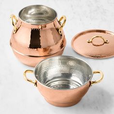 three copper pots with lids on a marble surface