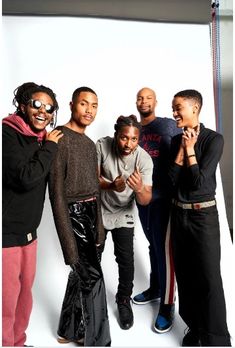 a group of men standing next to each other in front of a white background with one man holding his hand up