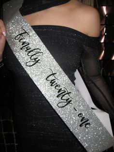 a woman wearing a black and silver sash with the words, thank you're here on it