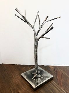 a metal tree sculpture sitting on top of a wooden floor