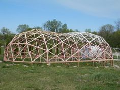 a large wooden structure sitting on top of a lush green field