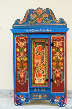 an ornately painted cabinet on display against a white wall