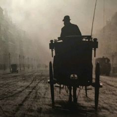 an old time photo of a man in a horse drawn buggy on a foggy street