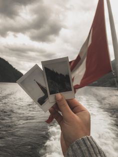 two polaroid photos being held up in front of a boat on the water with a canadian flag behind them