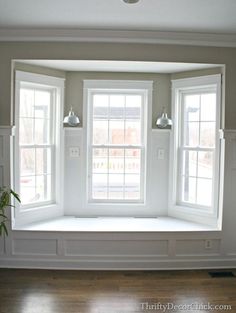 an empty room with three windows and white trim