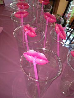 plastic cups with pink sticks sticking out of them on a purple tablecloth covered table