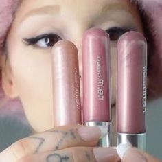 a woman holding three lipsticks in front of her face