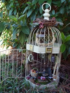 a birdcage filled with lots of items sitting in the middle of some grass