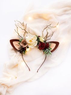 two deer headbands with flowers and antlers on top of a white cloth