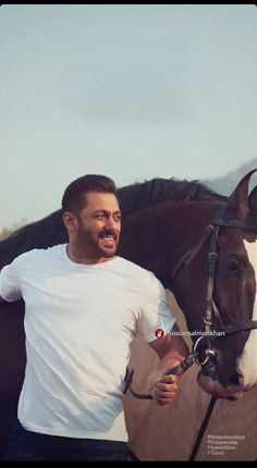 a man standing next to a brown and white horse with his hand on the bridle