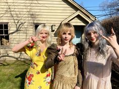 three women in dresses standing next to each other and making the v sign with their fingers