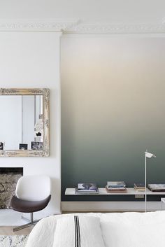 a living room with a chair, fireplace and mirror on the wall in front of it