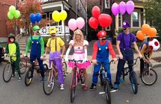 a group of people on bikes with balloons in the shape of heart shaped shapes and clowns