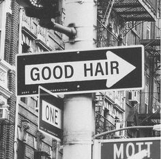 black and white photograph of street signs in new york city, with the words good hair on it