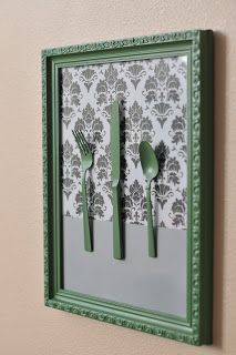 a green frame with forks and spoons in it on the side of a wall