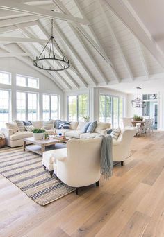 a large open living room with white furniture and wood flooring on the hardwood floors