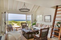 a living room filled with furniture and a fire place next to a window overlooking the ocean