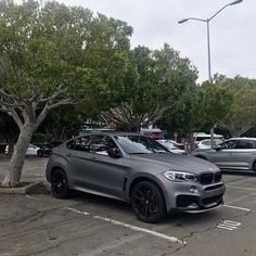 two cars parked in a parking lot next to trees