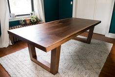 a wooden table sitting on top of a white rug in front of a blue wall