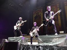 three men are performing on stage with guitars