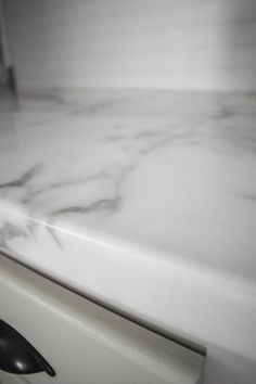 a close up view of a marble counter top with black handles and knobs on it