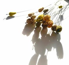 several crocheted flowers are hanging from a string on a white surface with long shadows