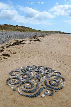 there is a large circle made out of rocks on the beach by the water and sand