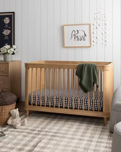 a baby's room with a crib, chair and teddy bear on the floor