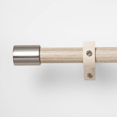 a close up of a wooden handle on a white curtain rod with two metal studs