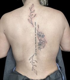 the back of a woman's upper body with flowers and words on her lower back