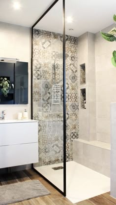 a bathroom with a glass shower door and wooden flooring next to a white sink