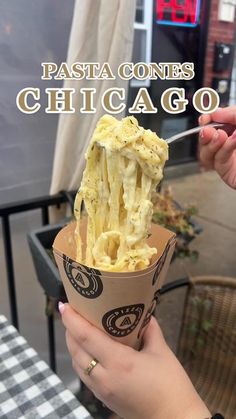 a person holding up a paper cup filled with food and the words pasta contes chicago above it