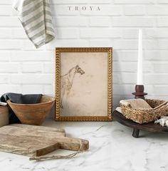 a white brick wall next to a wooden table with an old framed giraffe