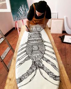 a man in an orange shirt is working on a large piece of art that looks like a squid