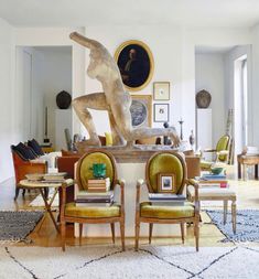 a living room filled with lots of furniture and art on the wall next to a statue