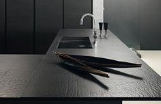 a bathroom sink sitting next to a faucet in a room with black walls