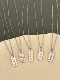 This listing is for a personalized engraved Japanese name dainty tag necklace in stainless steel. Stainless steel jewelry is strong and almost never tarnish or corrode.  The sample necklaces are engraved with Isabella in Japanese in the font #5 vertically and You are beautiful in Japanese in the font #2 in two vertical lines. If there are many characters, they will be engraved in two lines. Please check the font options in the pictures. The tag pendant is 6 mm wide and 15 mm high. The necklace is a 45 cm (17 inches) with a 5 cm (2 inches) extender chain. All orders come gift-wrapped. << How to order >> Please choose engraving side from the options. Please leave the name or word and font style number you want. If you don't choose a font, the font #5 used for the sample will be used. If you Personalized Rectangular Spiritual Necklace, Meaningful Engraved Rectangular Necklace, Everyday Silver Rectangular Name Necklace, Everyday Rectangular Silver Name Necklace, Rectangular Stainless Steel Necklaces With Engraved Text, Rectangular Stainless Steel Necklace With Engraved Text, Minimalist Stainless Steel Necklace With Engraving Option, Everyday Rectangular Necklace With Engraving Option, Everyday Rectangular Necklace With Engraved Text