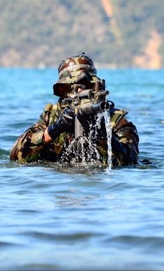 a soldier in camouflage wades through the water