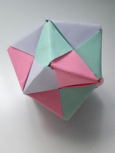 an origami ball with pink, blue and green colors on it sitting on a white surface