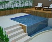 a pool with steps leading up to it next to a wooden fence and lawn chairs