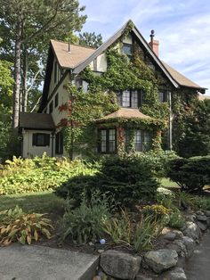 a house with ivy growing on the side of it's roof and landscaping around it