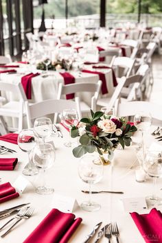 the table is set with white and red napkins, silverware, and wine glasses