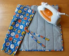 an ironing board with a blue and white flowered cloth next to it