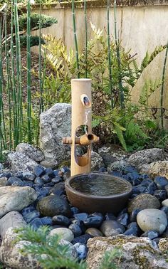 a water fountain surrounded by rocks and plants