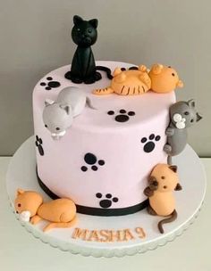 a cake decorated with cats and kittens on top of a white table next to a wall