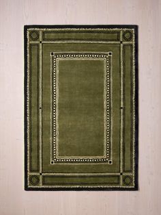 a green rug with an ornate border on the bottom and black border at the top