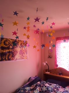 a bedroom with pink walls and colorful stars on the wall above the bed, in front of a window